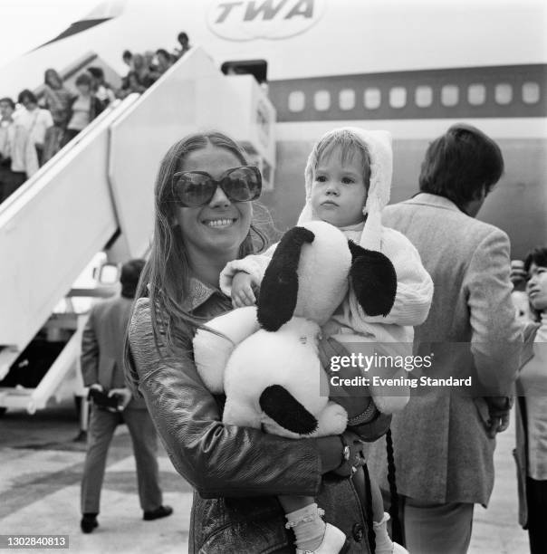 American actress Natalie Wood with her daughter Natasha at Heathrow Airport in London, UK, 4th August 1972. Natasha is holding a Snoopy toy.