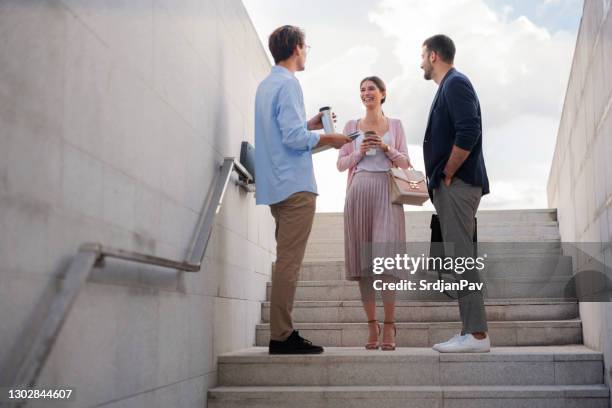 low angle view of smiling businesspeople talking outside - group of businesspeople standing low angle view stock pictures, royalty-free photos & images