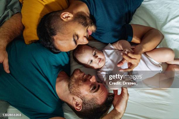 homosexuelles paar genießt zeit zu hause mit adoptiertem baby - two parents stock-fotos und bilder