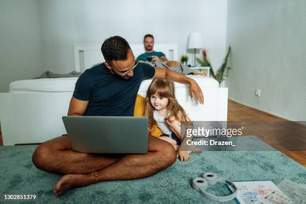 Mid adult gay couple with adopted daughter working from home during quarantine