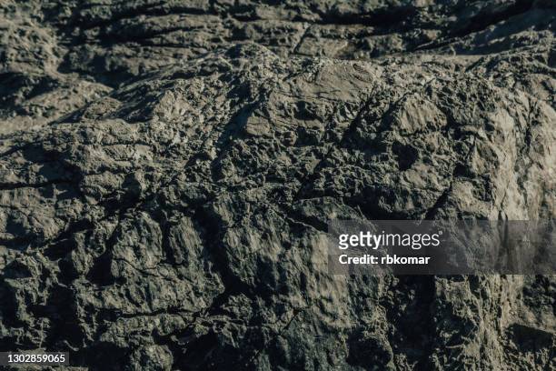 the texture of a barren brown stone with weathered cracks formed by nature. geological part of the rock close-up. abstract natural background - rock face fotografías e imágenes de stock
