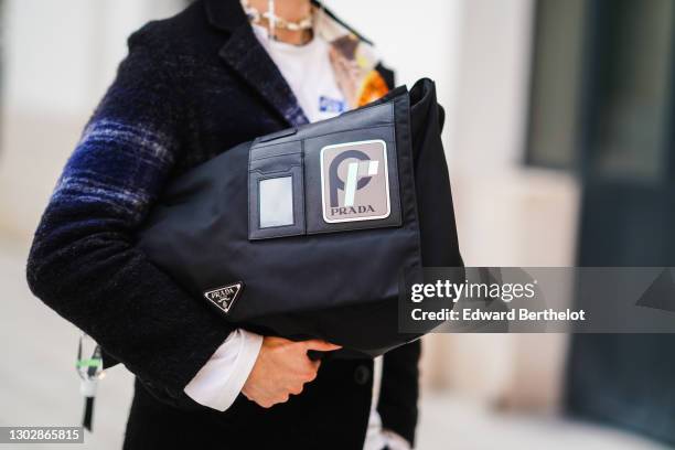 Andree Dubois wears a dark blue wool coat with printed checked pattern from Zara, a Prada large bag, on February 17, 2021 in Paris, France.