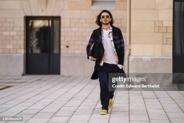 Andree Dubois wears green sunglasses, a sea-shell necklace, a white t-shirt with the printed FDJ Française des Jeux logo and Icepeak logo, a colored...