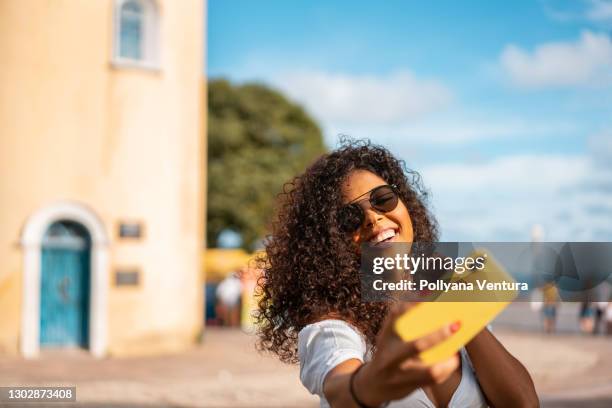 linda mulher de cabelo encaracolado tirando uma selfie - fotografar - fotografias e filmes do acervo