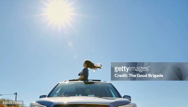 young girl looking out of sun roof in car on sunny day - soltak bildbanksfoton och bilder