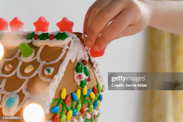 hand decorating gingerbread house cake - decorating a cake stock pictures, royalty-free photos & images