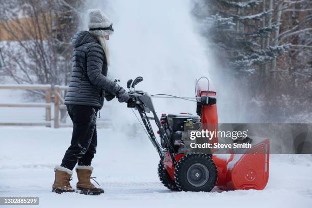 senior woman clearing snow using snowblower - snow blower stock pictures, royalty-free photos & images