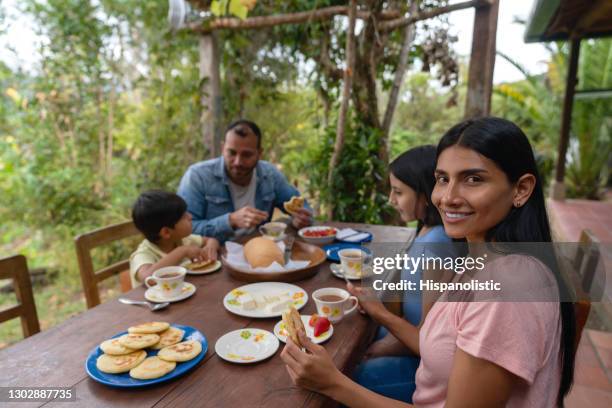 gelukkige latijns-amerikaanse vrouw die een traditioneel ontbijt thuis met haar familie eet - arepas stockfoto's en -beelden