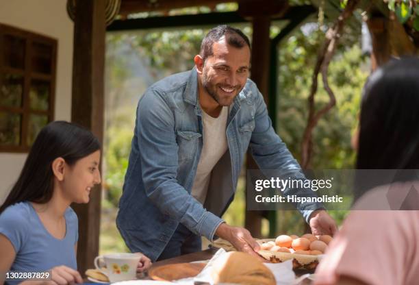 colombiaanse mens die een mand van eieren op de lijst voor ontbijt zet - man tray food holding stockfoto's en -beelden