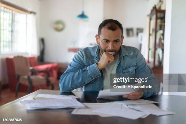 hombre de bajos ingresos revisando las finanzas de su casa y mirando preocupado - nota fotografías e imágenes de stock