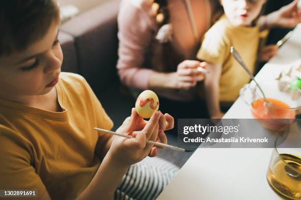 cute smal boy painting easter eggs at cozy home. - easter egg hunt stock-fotos und bilder