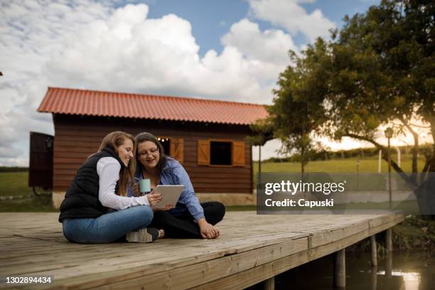 two women watching video on tablet at cabin deck - rustic cabin stock pictures, royalty-free photos & images