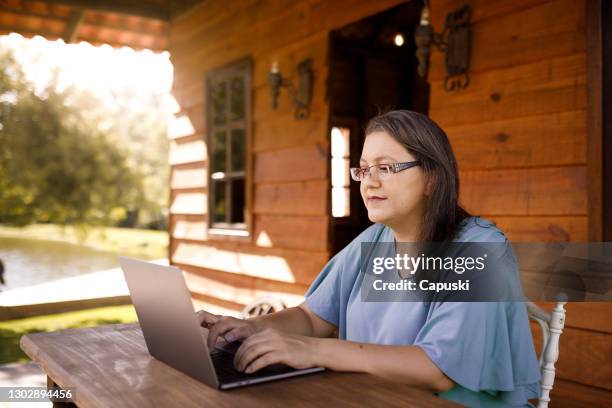 woman working on laptop at cabin outside - rural scene stock pictures, royalty-free photos & images