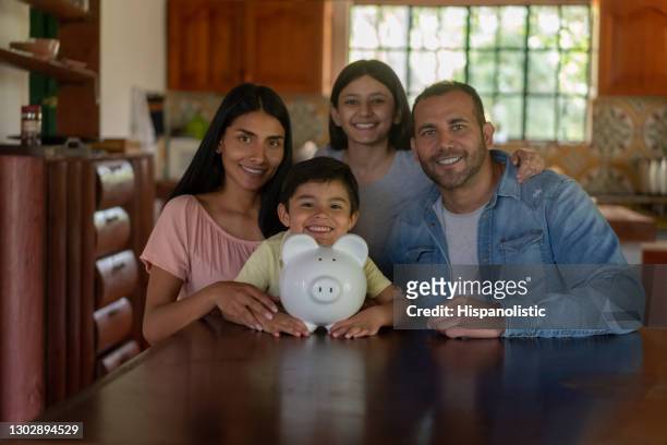 low income latin american family saving money in a piggybank - couple saving piggy bank stock pictures, royalty-free photos & images