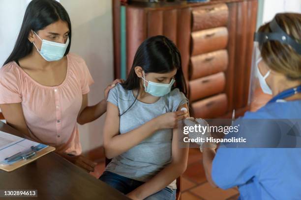 girl getting a covid-19 vaccine at her rural house - global health stock pictures, royalty-free photos & images