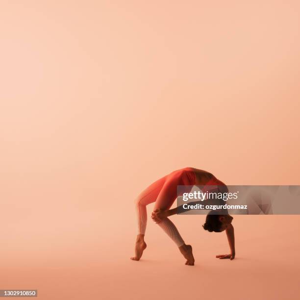 mature sporty woman wearing sportswear, pants and top, practicing yoga, studio shot - bending over backwards stock pictures, royalty-free photos & images