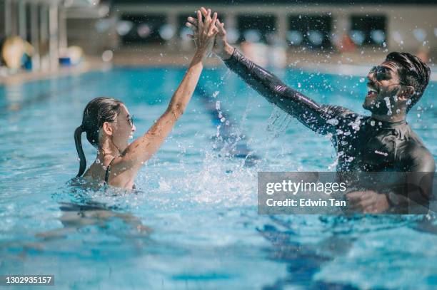 asian indian instructor giving high five to his student in the swimming pool achievement success - student athlete stock pictures, royalty-free photos & images