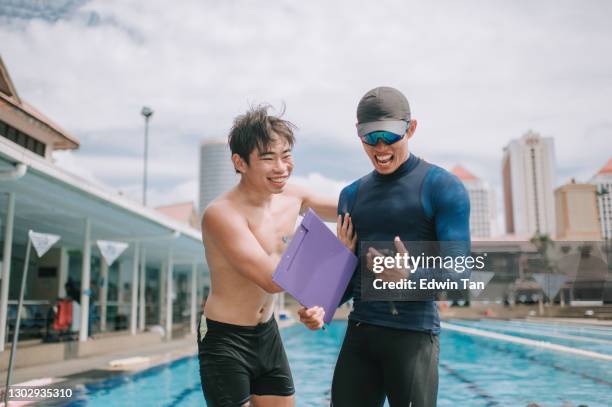 happy asian chinese personal trainer analysis showing his student record breaking on stopwatch the swimming exam result at pool side after education training class - bater o recorde imagens e fotografias de stock