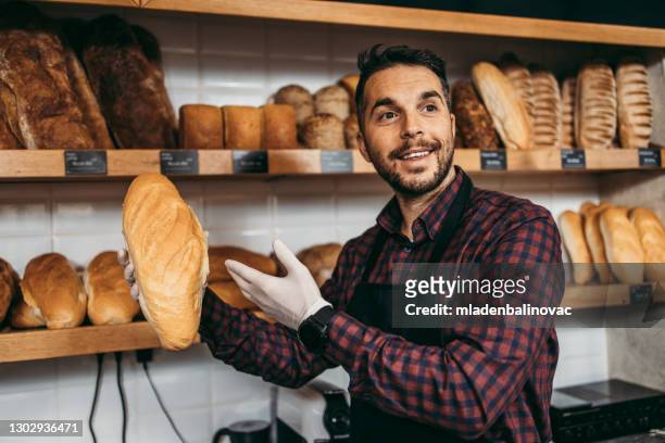 handsome middle age male worker working in bakery. - man offering bread stock pictures, royalty-free photos & images