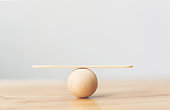 Wooden seesaw scale empty balancing on wooden sphere on wood table