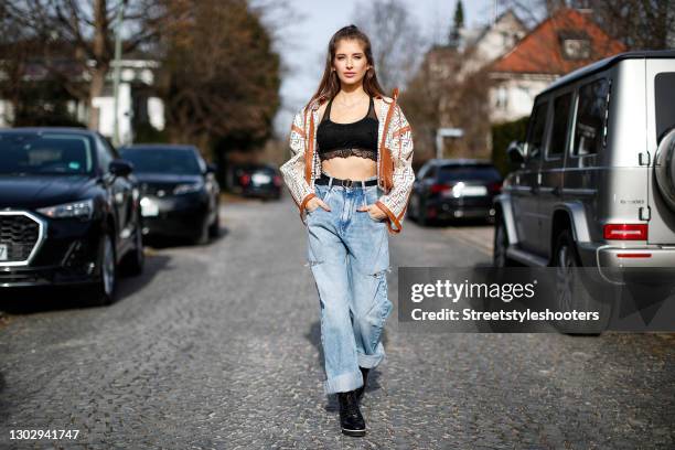 Influencer and TV host Cathy Hummels wearing black boots by Chanel, light blue vintage ripped denim jeans pants, a black belt by Asos, a black...