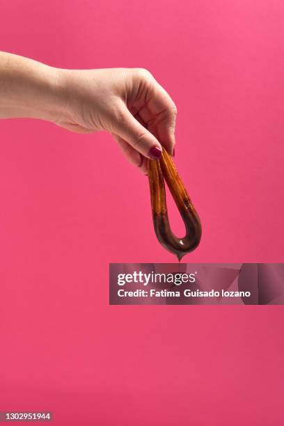 one hand with churro in hand dipping in the glass with chocolate - chocolate con churros stock pictures, royalty-free photos & images