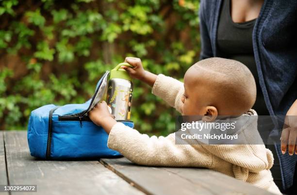 a young boy opening his lunch box to get food to eat. - flask stock pictures, royalty-free photos & images