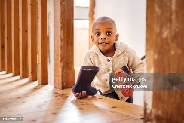 cute young boy walking up the staircase at home holding his rubber rain boots - new adventure stock pictures, royalty-free photos & images