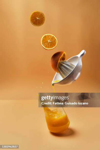 oranges and juice squeezer levitating while making fruit juice - drink coaster stock pictures, royalty-free photos & images