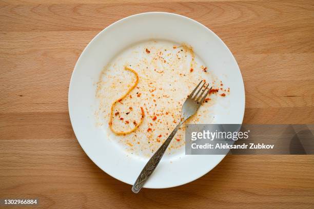 a dirty empty plate of pasta or spaghetti, a fork on a wooden table. used cutlery, symbolize the end of lunch or dinner. - piatto descrizione generale foto e immagini stock