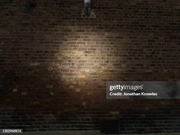 spotlight on brick wall - bricks fotografías e imágenes de stock