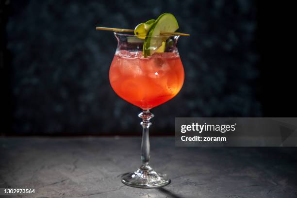 red cocktail in wine glass with grape and apple slices on cocktail stick - garnish stock pictures, royalty-free photos & images