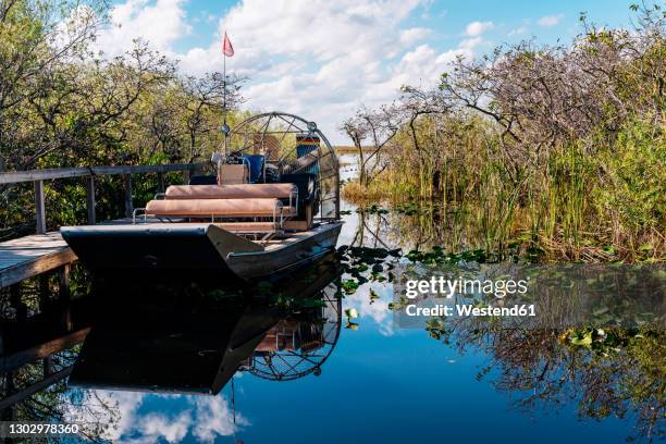 airboat by pier in lake against sky at everglades national park - everglades nationalpark stock-fotos und bilder