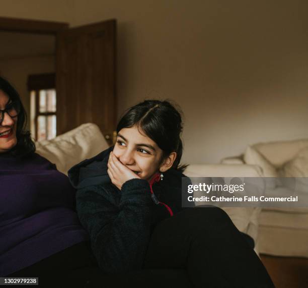 girl rests her chin on her hand and leans in towards her mum, and smiles - two young arabic children only indoor portrait stock-fotos und bilder