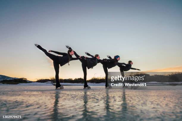 female figure skaters practicing on frozen lake at dusk - match sport stockfoto's en -beelden