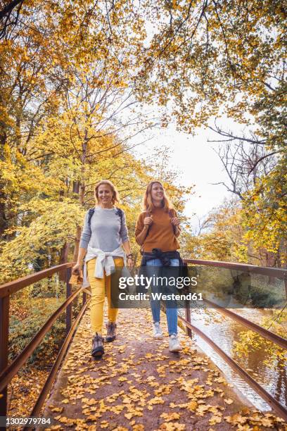 women smiling while walking on bridge in forest - schritt natur stock-fotos und bilder