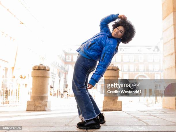 smiling woman bending backwards while standing on footpath - head back stock pictures, royalty-free photos & images