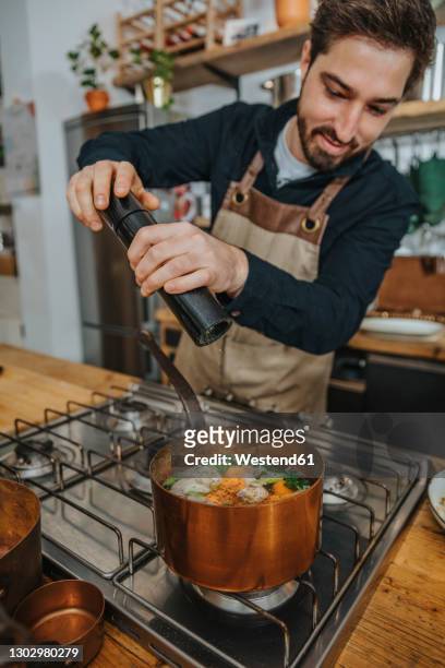 expertise putting pepper on broth soup while cooking in copper saucepan in kitchen - pepper mill stock pictures, royalty-free photos & images