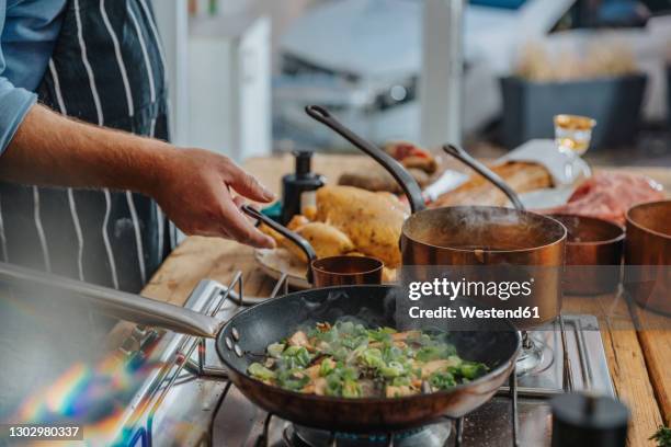 male expertise cooking king oyster mushroom and scallions in frying pan while standing in kitchen - köksredskap bildbanksfoton och bilder