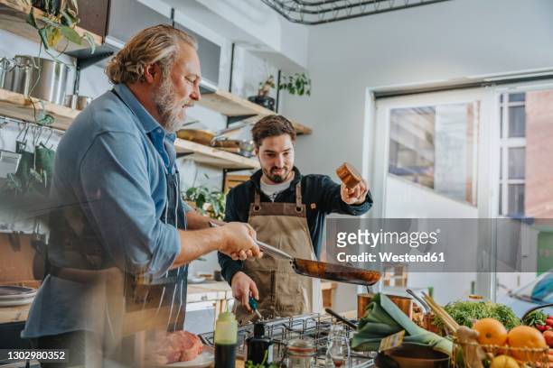 chef team preparing food while standing in kitchen - chef tossing fire stock-fotos und bilder