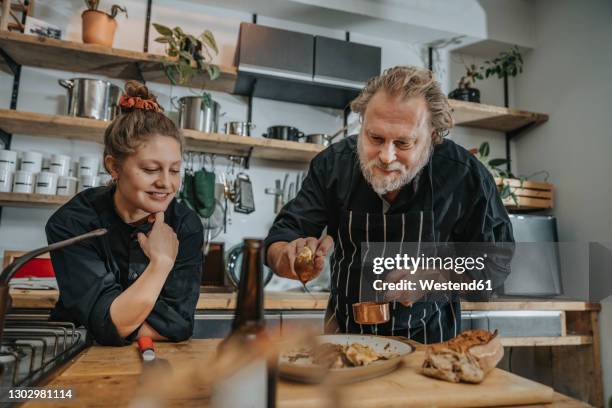 mature expertise putting sauce over food while standing in kitchen - chef cuisinier sauce photos et images de collection