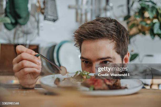 chef concentrating while garnishing tomahawk steak with vegetable in kitchen - rich man stock-fotos und bilder