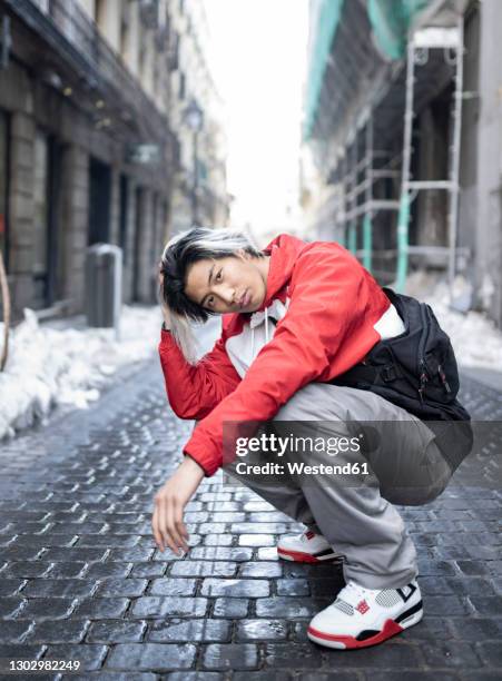 male hipster with hand in hair on street in city - asian man long hair stock pictures, royalty-free photos & images