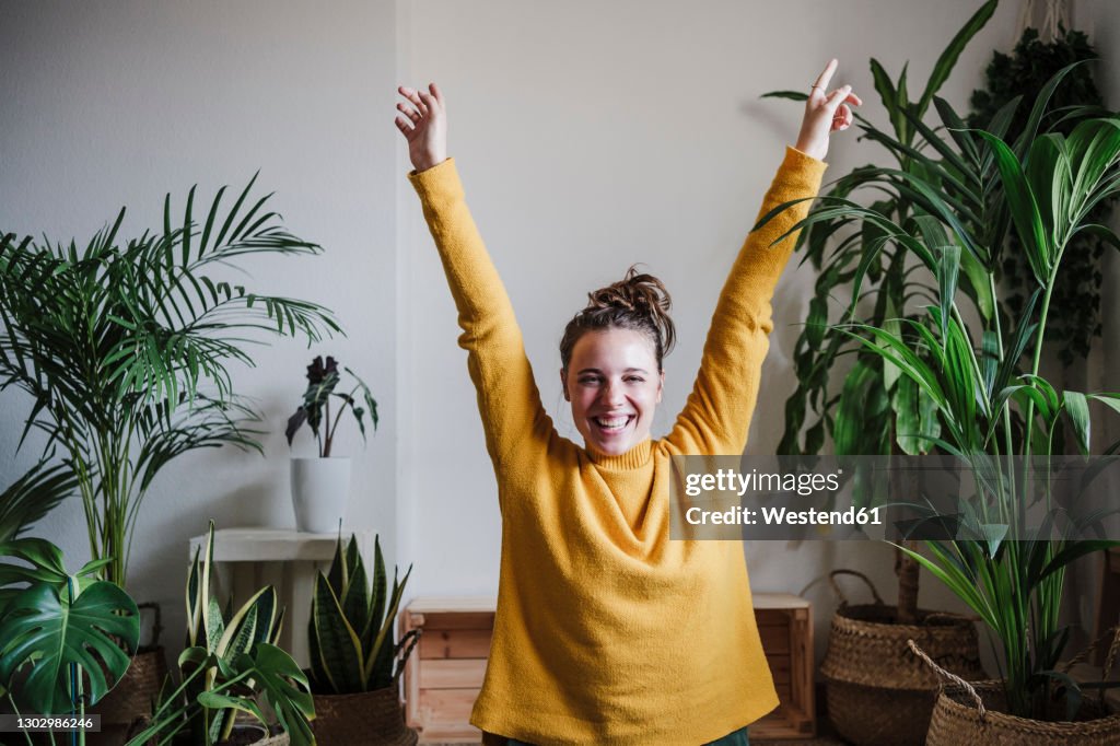 Carefree woman with hand raised sitting at home