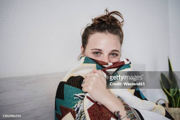 woman wrapped in blanket staring while sitting on bed at home - wrapped in a blanket stock pictures, royalty-free photos & images