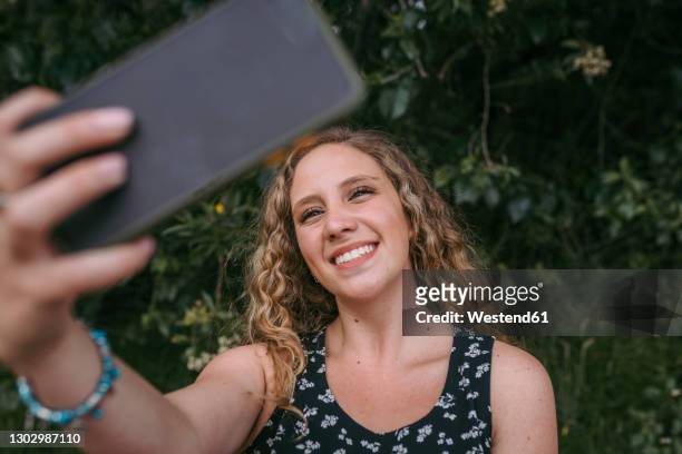 beautiful smiling woman taking selfie in public park - blonde woman selfie stock pictures, royalty-free photos & images