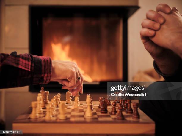 couple playing chess by fireplace at home during winter - chess board without photos et images de collection