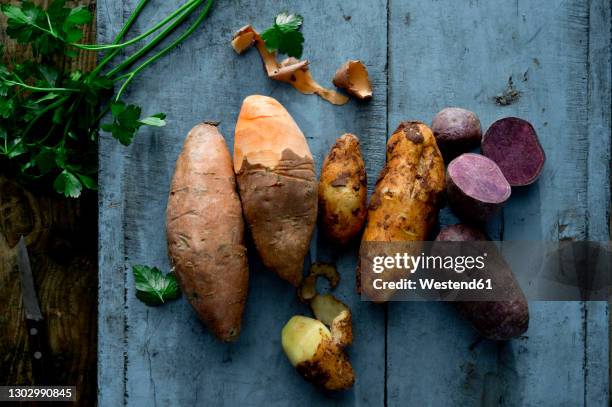 parsley and different varieties of potatoes lying on wooden surface - zoete aardappel stockfoto's en -beelden