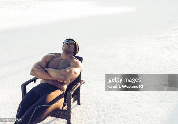mid adult sportsman wearing sunglasses resting while sitting with arms crossed on chair in snow - man sleeping with cap stock pictures, royalty-free photos & images