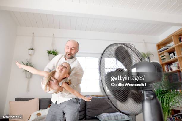 father having fun with daughter imitating airplane at home - ventilator stock-fotos und bilder